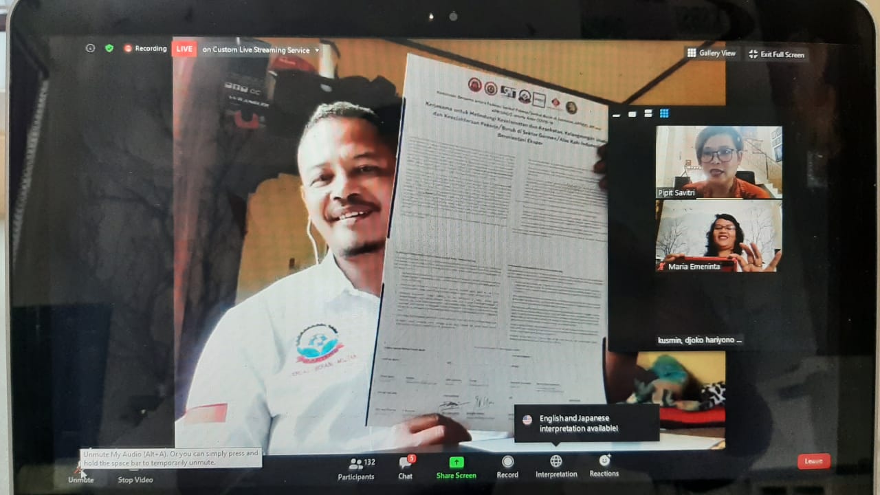 Ari Joko, vakbondsleider in de textielsector in Indonesië laat trots de overeenkomst zien die gesloten is met werkgeversorganisaties toont de overeenkomst die is gesloten met werkgeversorganisaties over gezamenlijke inzet om de gevolgen van de coronacrisis aan te pakken