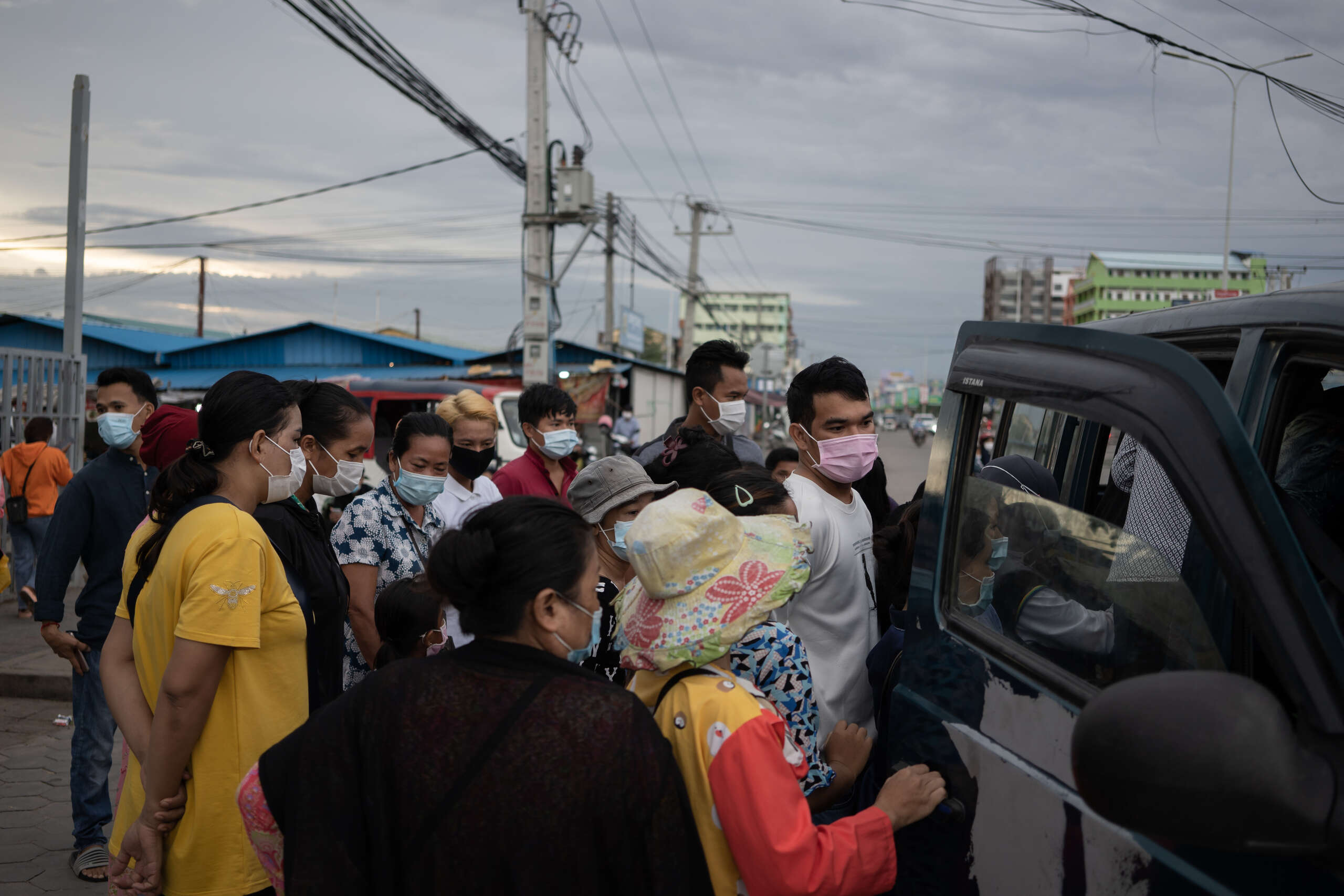 Garment workers in Cambodia standing near a car.